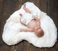 Baby lying on white soft duvet designed as heart.