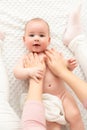 Baby massage. Female therapist gently massaging newborn baby boy. Mother applying body lotion to her infant baby boy.