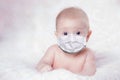 The baby is in a medical mask is lying on the bed. Concept pandemic coronavirus Covid 19