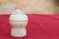 Baby milk in bottle and breastmilk in storage bags on red towel