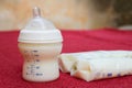 Baby milk in bottle and breastmilk in storage bags on red towel