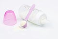 Baby milk bottle with pink cap and pink measuring spoon with powder milk Royalty Free Stock Photo