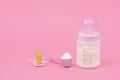 Baby milk formula feeding bottle, pacifier on a pastel pink background Royalty Free Stock Photo