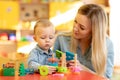 Baby minder playing with kid in nursery Royalty Free Stock Photo