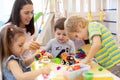 Baby minder playing with kids in day care center