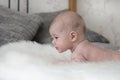 Baby 3 months lying on a fluffy bedspread on the bed, baby girl boy. Head of a small child, look to the side, soft focus Royalty Free Stock Photo