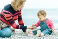 Baby and mother play with pebbles on the beach