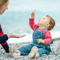Baby and mother playing with pebbles on the beach