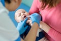 Baby on mothers hand at hospital. Nurse making infant oral vaccination against rotavirus infection. Children health care