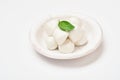 Baby mozzarella cheese with basil leaf in white ceramic plate isolated on white background. Group of bocconcini mozzarella Royalty Free Stock Photo