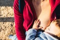 Baby naps while being breastfed by his mother outdoors