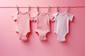 Baby newborn girl pink bodysuits on a line on pink background. Laundry day, baby clothes, baby shower theme Royalty Free Stock Photo