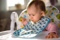 Baby not liking the food and spits it out. Sitting in a high chair in bright living room. 6- 12 months old. Feeding baby concept Royalty Free Stock Photo