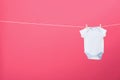 Baby onesie hanging on clothes line against background, space for text Royalty Free Stock Photo