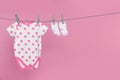 Baby onesie and socks drying on laundry line against pink background, space for text Royalty Free Stock Photo