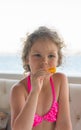 Baby with orange. Happy little girl eating orange near the sea.