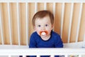 Baby with pacifier in white bed Royalty Free Stock Photo