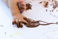 Baby painting with hands with chocolate