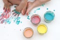 Baby painting with her hands. Homemade colorful paints for a baby in glass jars. Dough and food colorants on a white background.