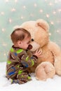 Baby in pajamas kissing teddy bear Royalty Free Stock Photo