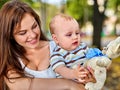 Baby in park outdoor. Kid with toy on mom`s hands. Royalty Free Stock Photo