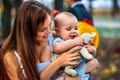 Baby in park outdoor. Kid with toy on mom`s hands. Royalty Free Stock Photo