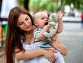 Baby in park outdoor. Kid with toy on mom`s hands. Royalty Free Stock Photo