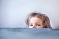 A baby peeks out of bed. Close-up of the head and eyes. Family hide and seek at home. Royalty Free Stock Photo