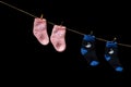 Baby Pink and blue socks hang on a pin on a rope. On a black background Royalty Free Stock Photo