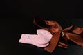 Baby pink socks with a bow are lying on a black table, on a black background. Royalty Free Stock Photo