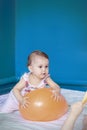 Baby playing with a balloon. Baby girl doing her daily activities. Little cute girl learning to stand up and walk