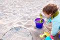 Baby playing with buckets and plastic toy shovels in a sandbox Royalty Free Stock Photo