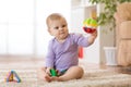 Baby playing with colorful toys sitting on a carpet at home Royalty Free Stock Photo