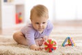 Baby playing with colorful toys sitting on a carpet at home Royalty Free Stock Photo