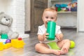 A baby is playing on the floor. The boy is sitting on the floor. The child takes the toy into his mouth and licks it Royalty Free Stock Photo