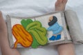 Baby playing with handmade textile book. Child holding an ineractive book with funny felt toys. Early development.