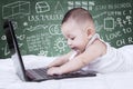 Baby playing laptop on bed with doodles background Royalty Free Stock Photo