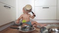 baby playing pots in the kitchen on the floor. happy family kid dream concept. baby scattered pots play dabble sitting