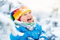 Baby playing with snow in winter. Child in snowy park. Royalty Free Stock Photo