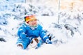 Baby playing with snow in winter. Child in snowy park. Royalty Free Stock Photo