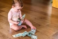Baby playing with some dollar bills he has found on the floor of his house, eating money Royalty Free Stock Photo