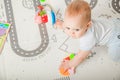 Baby plays on floor with educational toys, rattles and teething toys. Crawling babies at 8 months