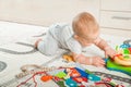 Baby plays on floor with educational toys, rattles and teething toys. Crawling babies at 8 months