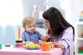 Baby boy plays with mother or teacher in nursery or day care centre