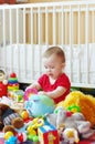 Baby plays toys against white bed