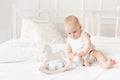 Baby plays with wooden toys cubes on the bed in a bright room