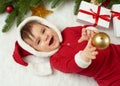 Baby portrait in christmas decoration, dressed as Santa, lie on fur near fir tree and play with gifts, winter holiday concept Royalty Free Stock Photo