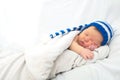 Baby portrait with jaundice, sleeping newborn in hat on white blanke