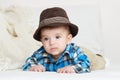 Baby portrait lie on white towel in bed, dressed in plaid shirt and hat Royalty Free Stock Photo