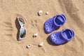 Baby purple clog and sunglasses on the sand on the beach. Cute details of summer holidays. Baby shoes on the beach. Royalty Free Stock Photo